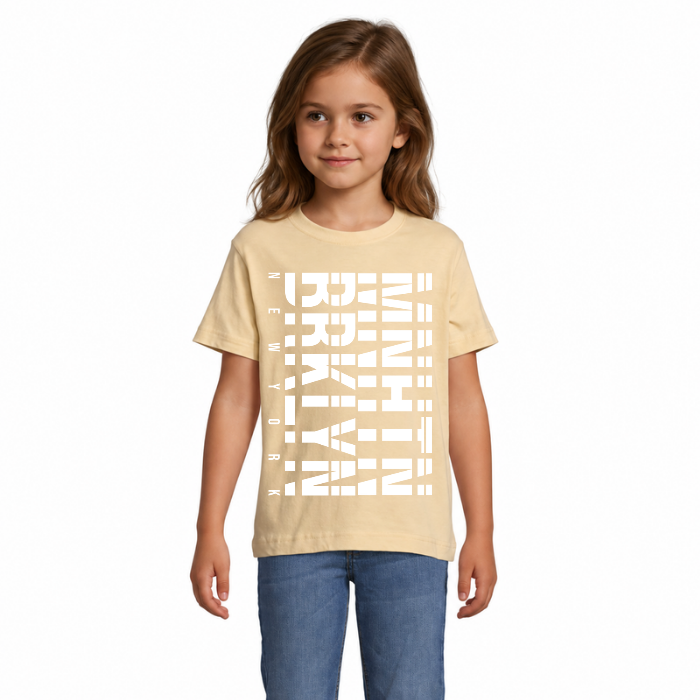 Barn i beige T-shirt med stort vitt Brooklyn Manhattan-tryck, horisontella linjer och mindre New York-text längs sidan.
