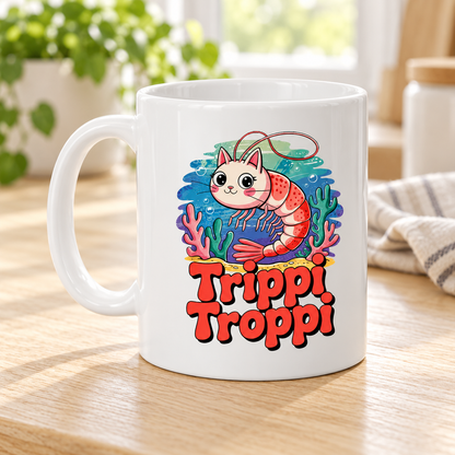 Vit mugg med Trippi Troppi som en rosa katt med räkkropp bland färgglada koraller och bubblor, ovanför röd text.