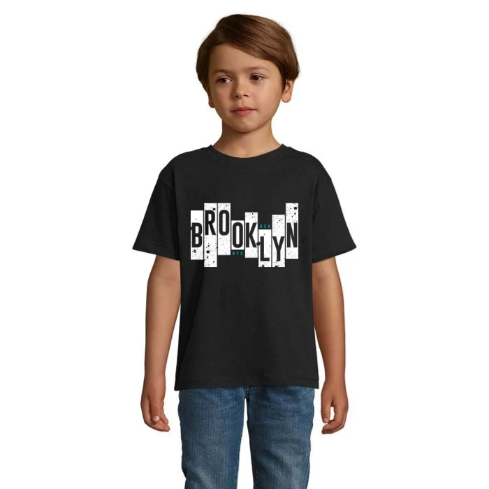 Barn i svart T-shirt med Brooklyn-text i svarta bokstäver på vita fält i olika höjder, sliten struktur och små turkosa detaljer.