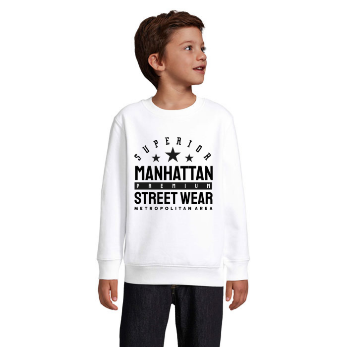 Barn i vit sweatshirt med svart Manhattan Street Wear-text, tre stjärnor och bågformad Superior-text på bröstet.