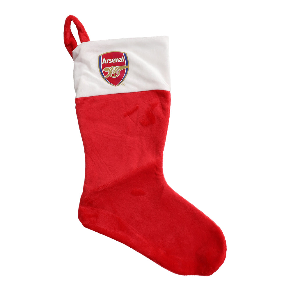 En röd och vit julstrumpa med Arsenal FC-logotypen hängande vid en öppen spis.