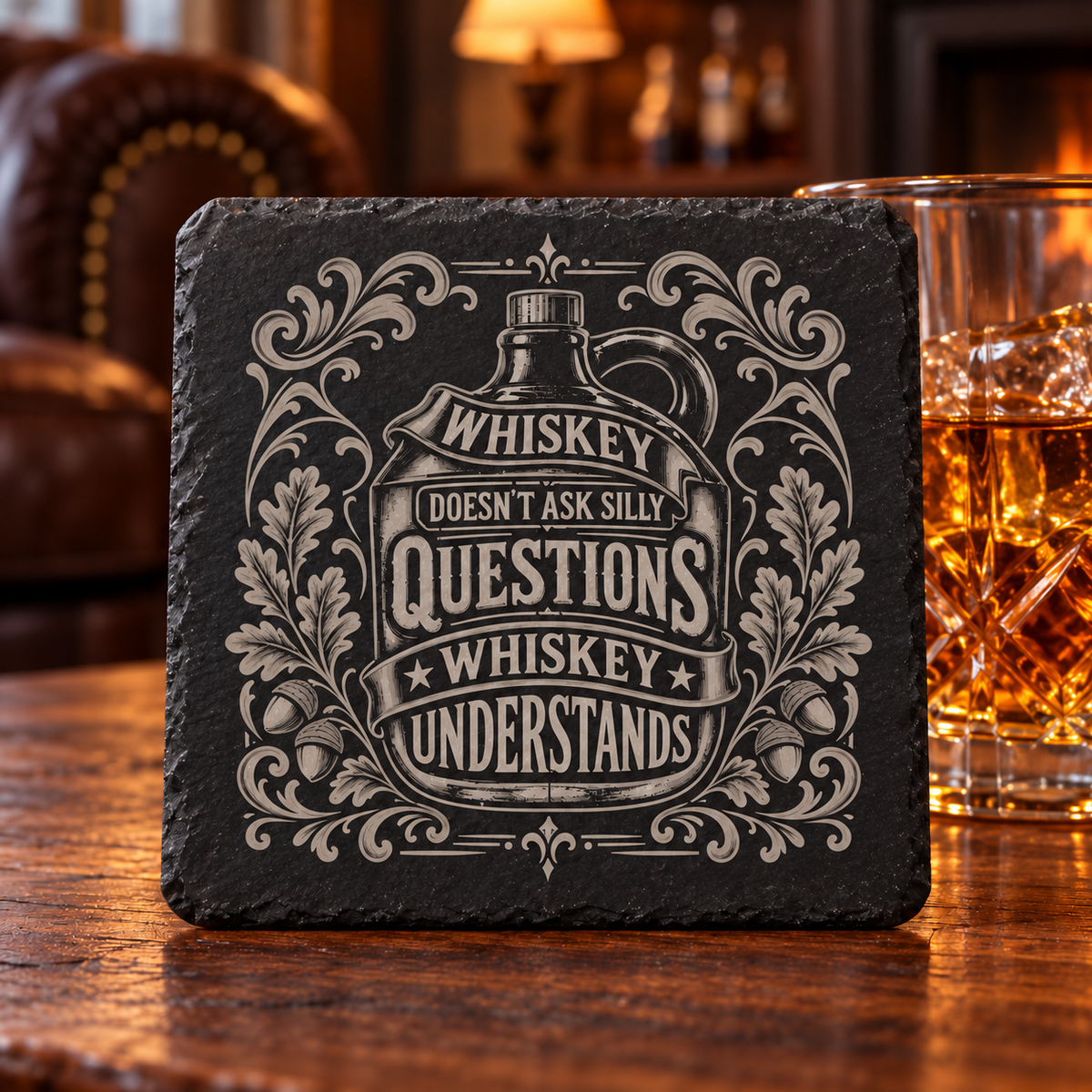 Glasunderlägg i skiffer med whiskeyflaska, ekblad och texten Whiskey Doesn’t Ask Silly Questions, Whiskey Understands.