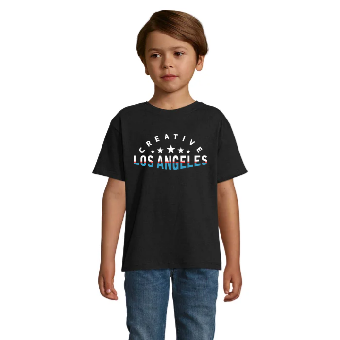 Barn i svart T-shirt med vit Creative-text i en båge, vita stjärnor och Los Angeles-text i vitt med blå detaljer.