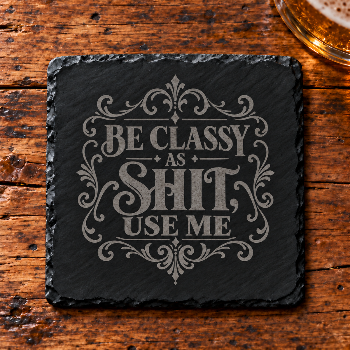 Glasunderlägg i skiffer med texten Be Classy as Shit, Use Me och en ram av dekorativa ornament.