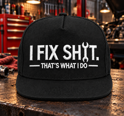 Svart snapbackkeps med vit I Fix Shit-brodyr och skiftnyckel i verkstadsmiljö
