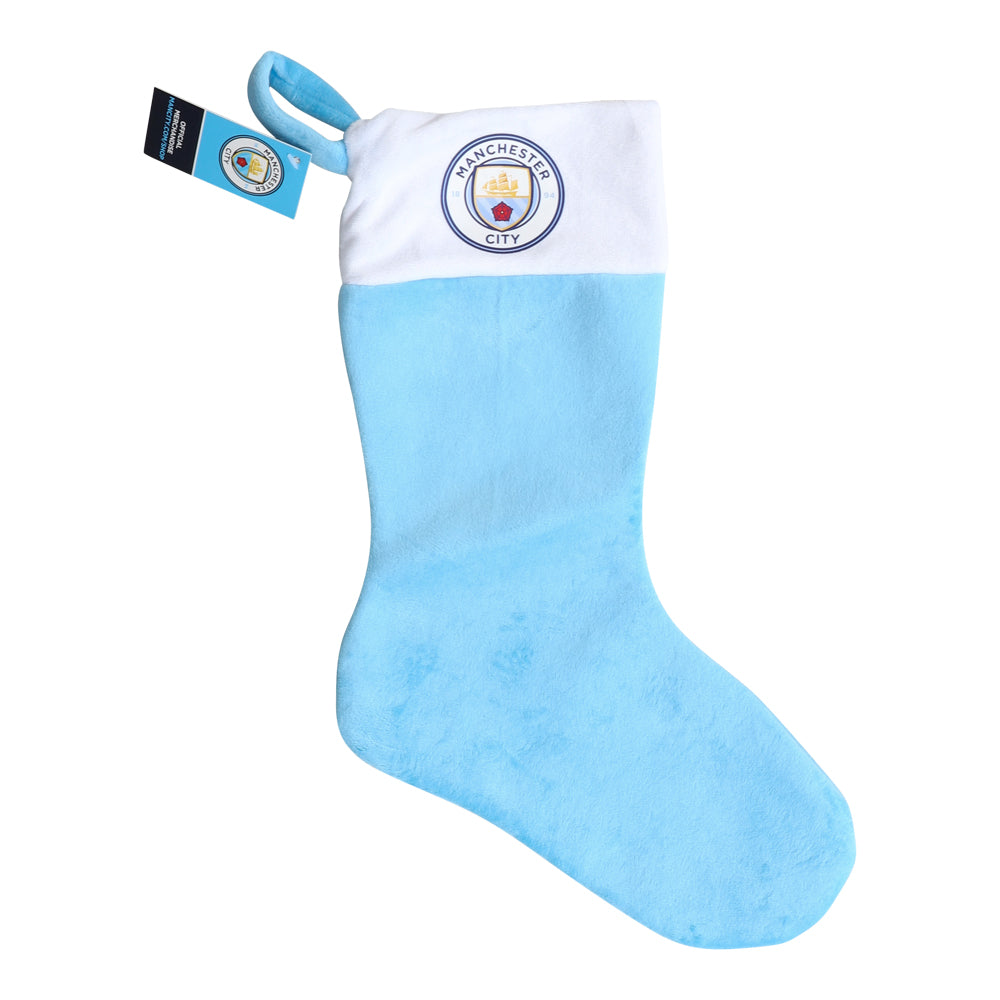 En stilren ljusblå julstrumpa prydd med Manchester City FC-logotypen hängande i ett mysigt rum.